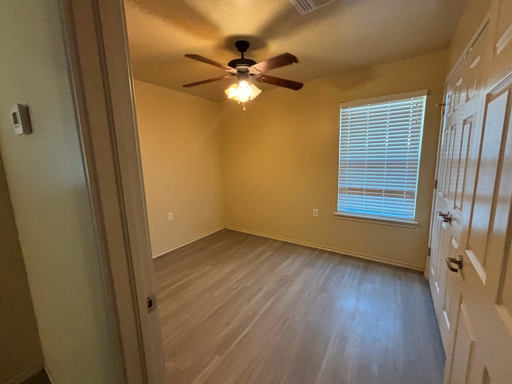 Bedroom with ceiling fan, wood-look flooring, and a bright window