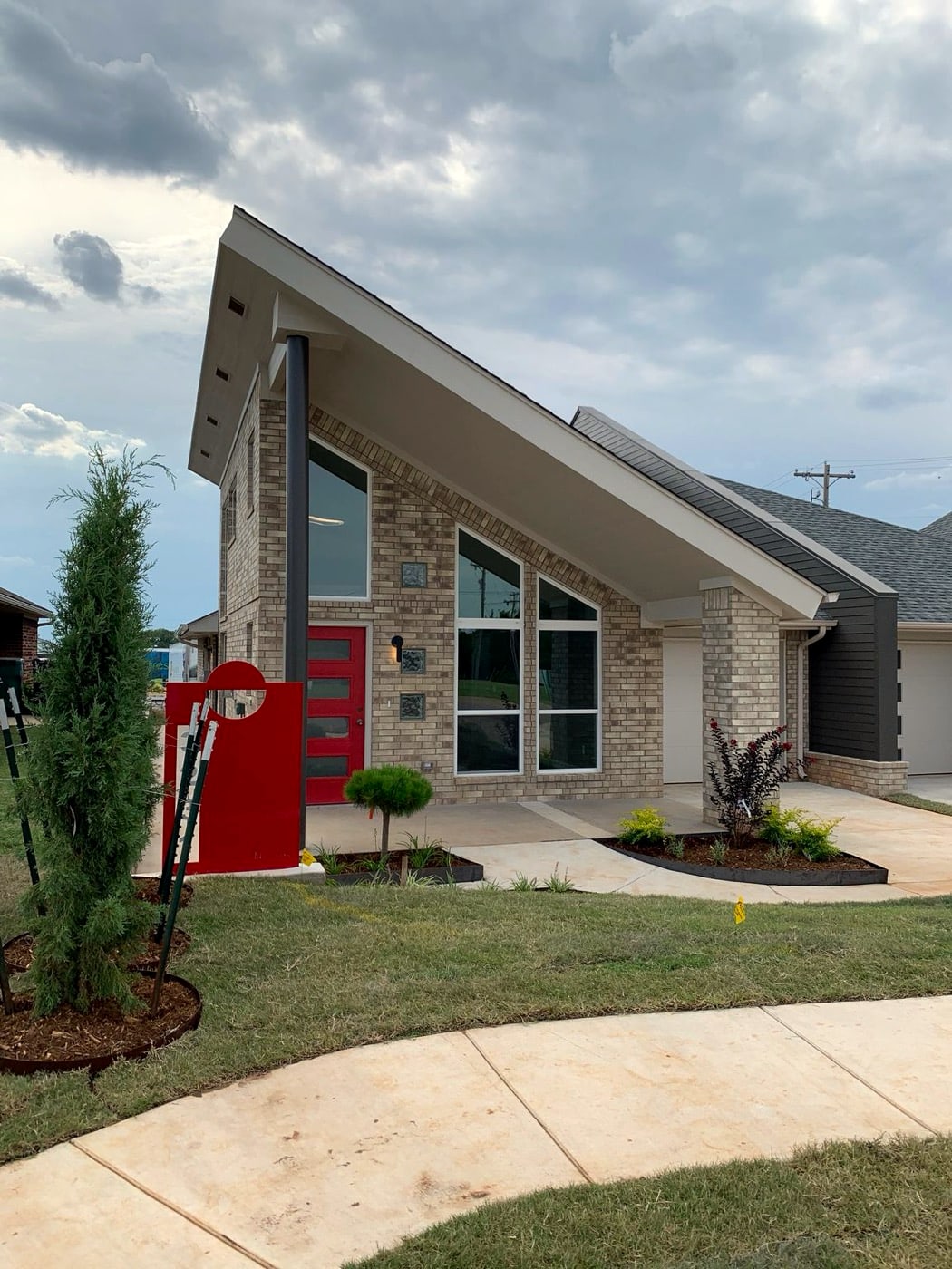 Front exterior of a brick Forest Village duplex with a red front door