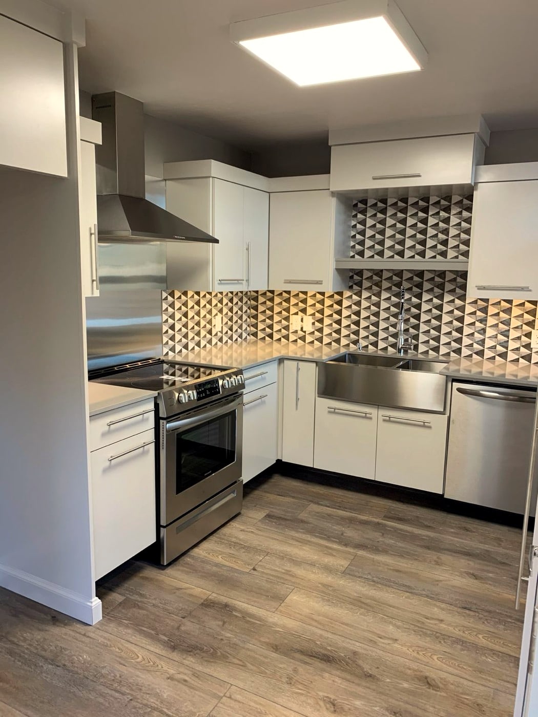 Kitchen with stainless range, vent hood, and quartz counters