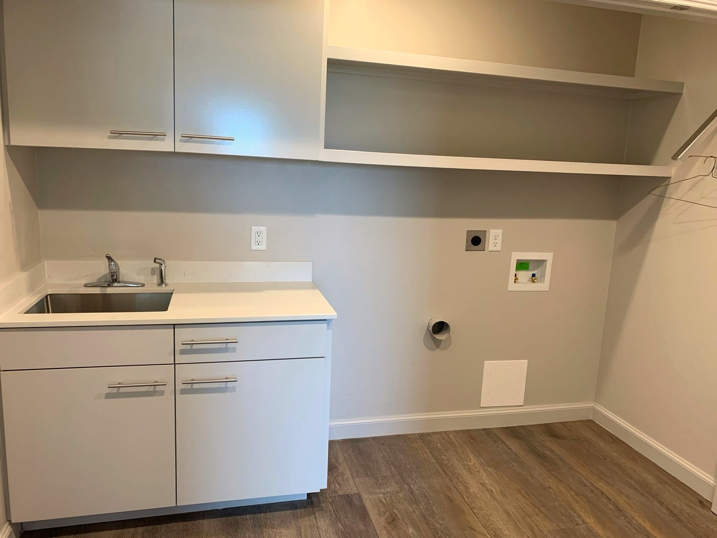 Laundry room with utility sink, cabinets, and hanging rod