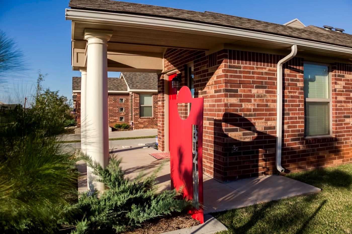 Signature red front door and brick porch of a Forest Village home